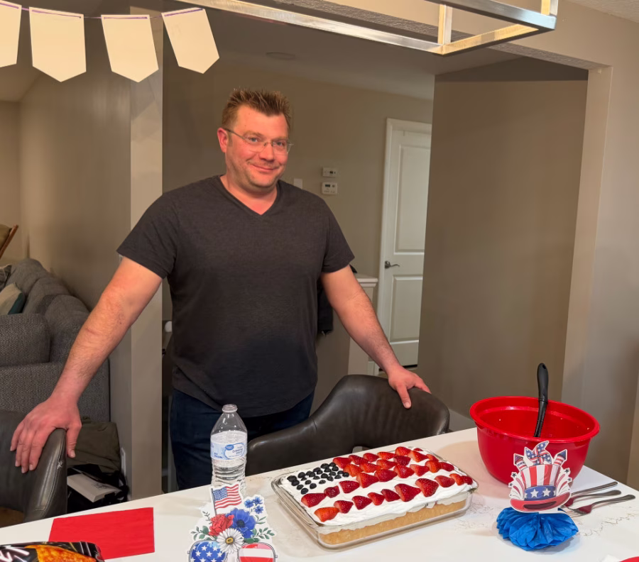 Man standing in front of a US flag decorated cake.