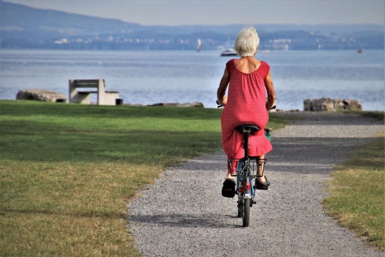 Senior woman riding a bike by the ocean.