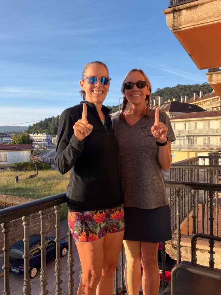 Two women holding up one finger each, indicating the number one.