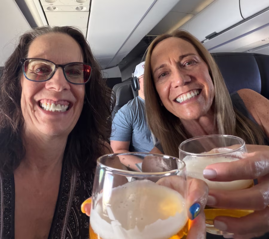 Two women toasting on an airplane.