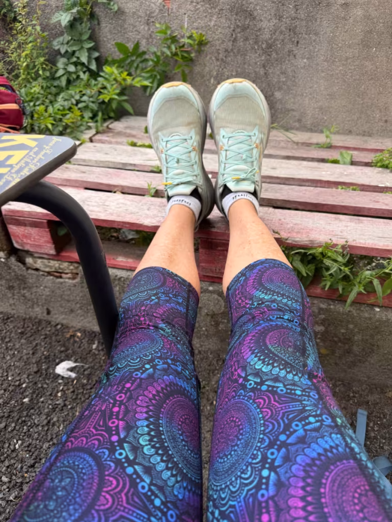 A woman's feet in dirty walking shoes propped up on a bench.