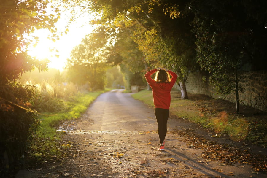 A woman walking on a wooded trail.