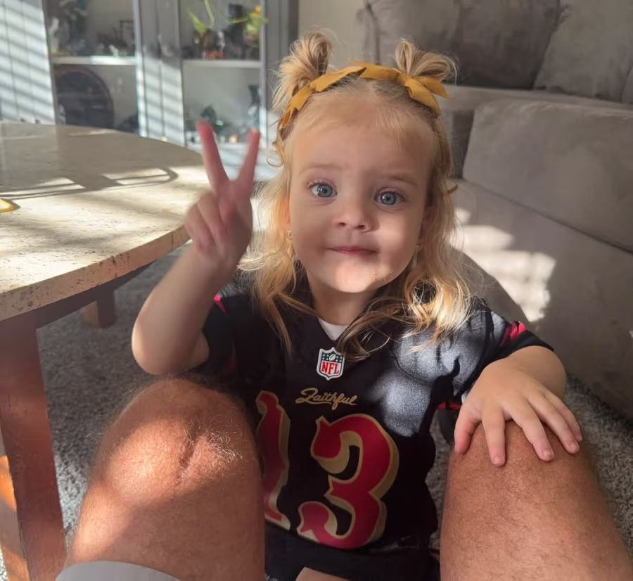 Toddler girl holding up peace sign.